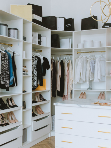a white closet with clothing and shoes.