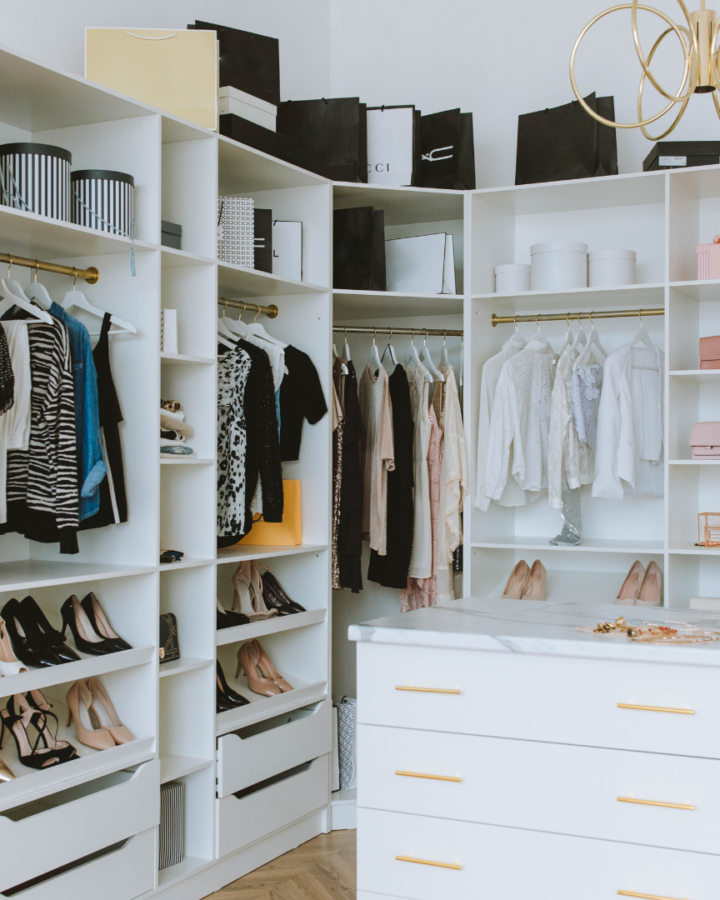 a white closet with clothing and shoes.