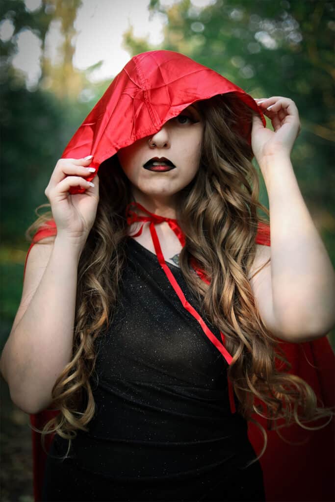 woman in a halloween costume with a red hooded cape with a black shirt with sparkles.