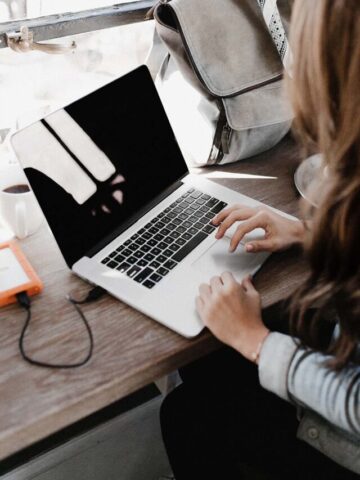 woman sitting beside table while using macbook.