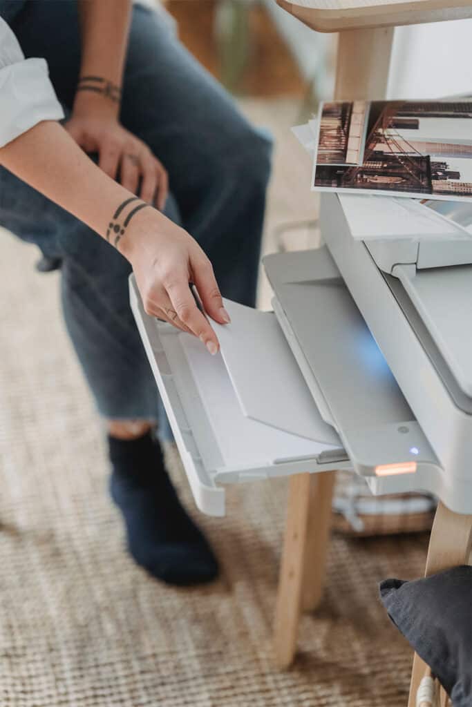 woman putting white printer paper into a tray of a printer.