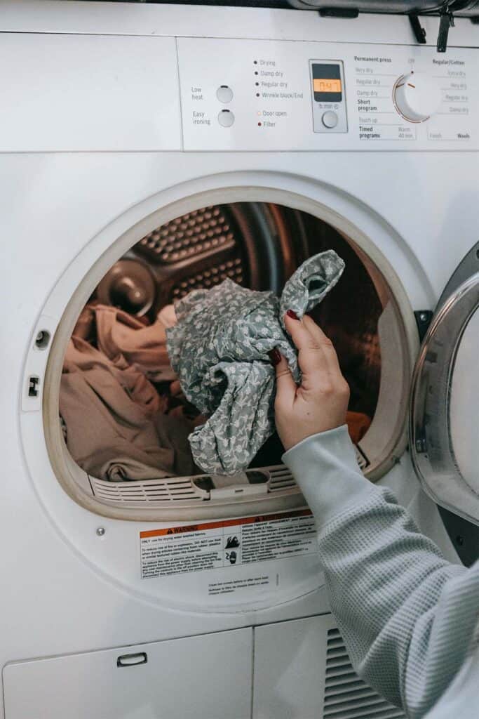 woman putting clothing item into washing machine