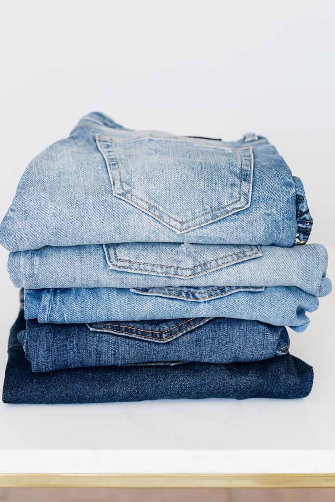 a stack of five folded pairs of blue jeans.