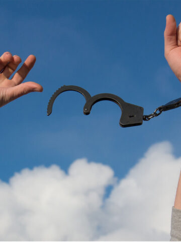 a person with their hands in the air with a handcuff on one arm.