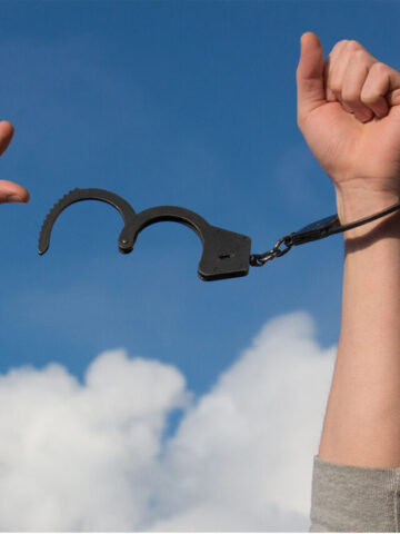 a person with their hands in the air with a handcuff on one arm.