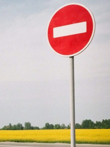 no entry sign in front of a field of yellow flowers.