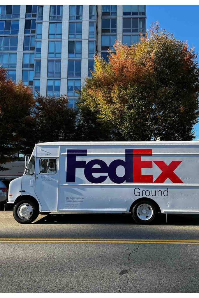 a fedex ground truck parked on an asphalt road.