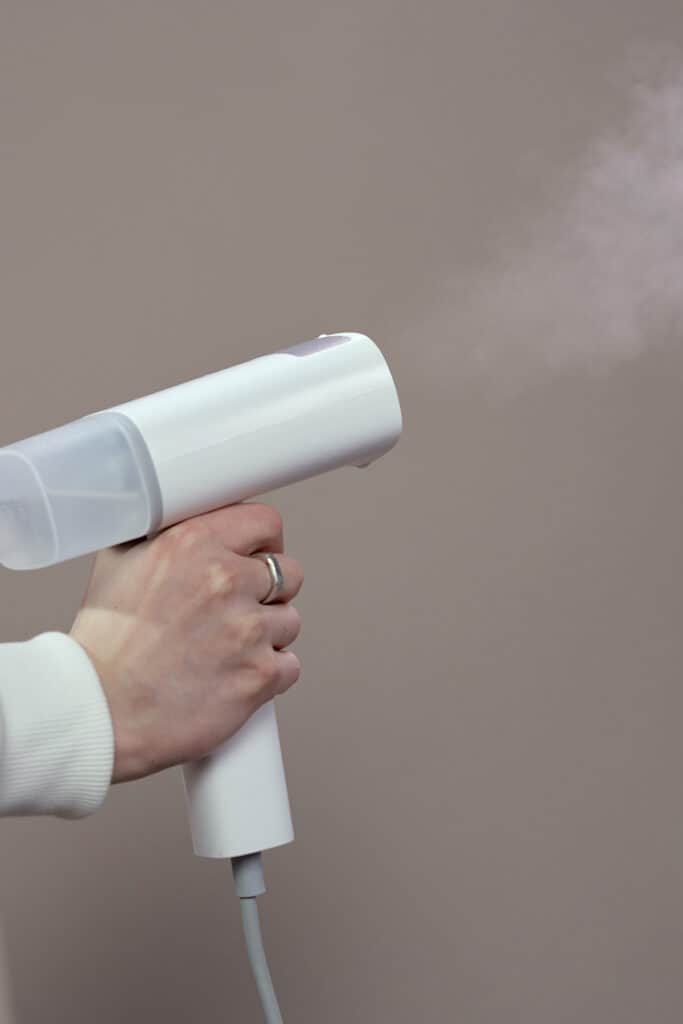 person holding a white plastic steamer.