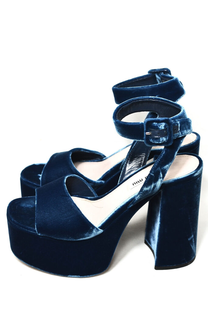 a pair of blue suede heels on a white backdrop.