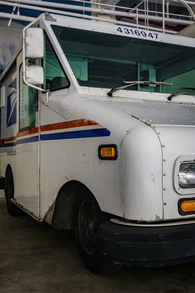 a united states postal service mail truck on concrete.