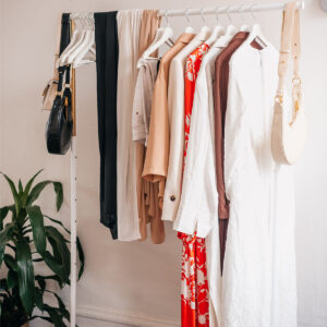 clothing and purses hanging on a white clothing rack.