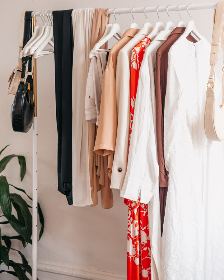 clothing and purses hanging on a white clothing rack.