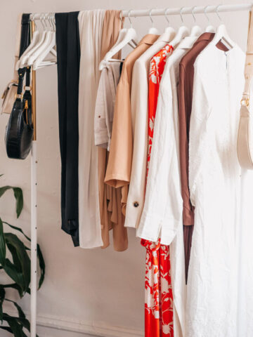 clothing and purses hanging on a white clothing rack.