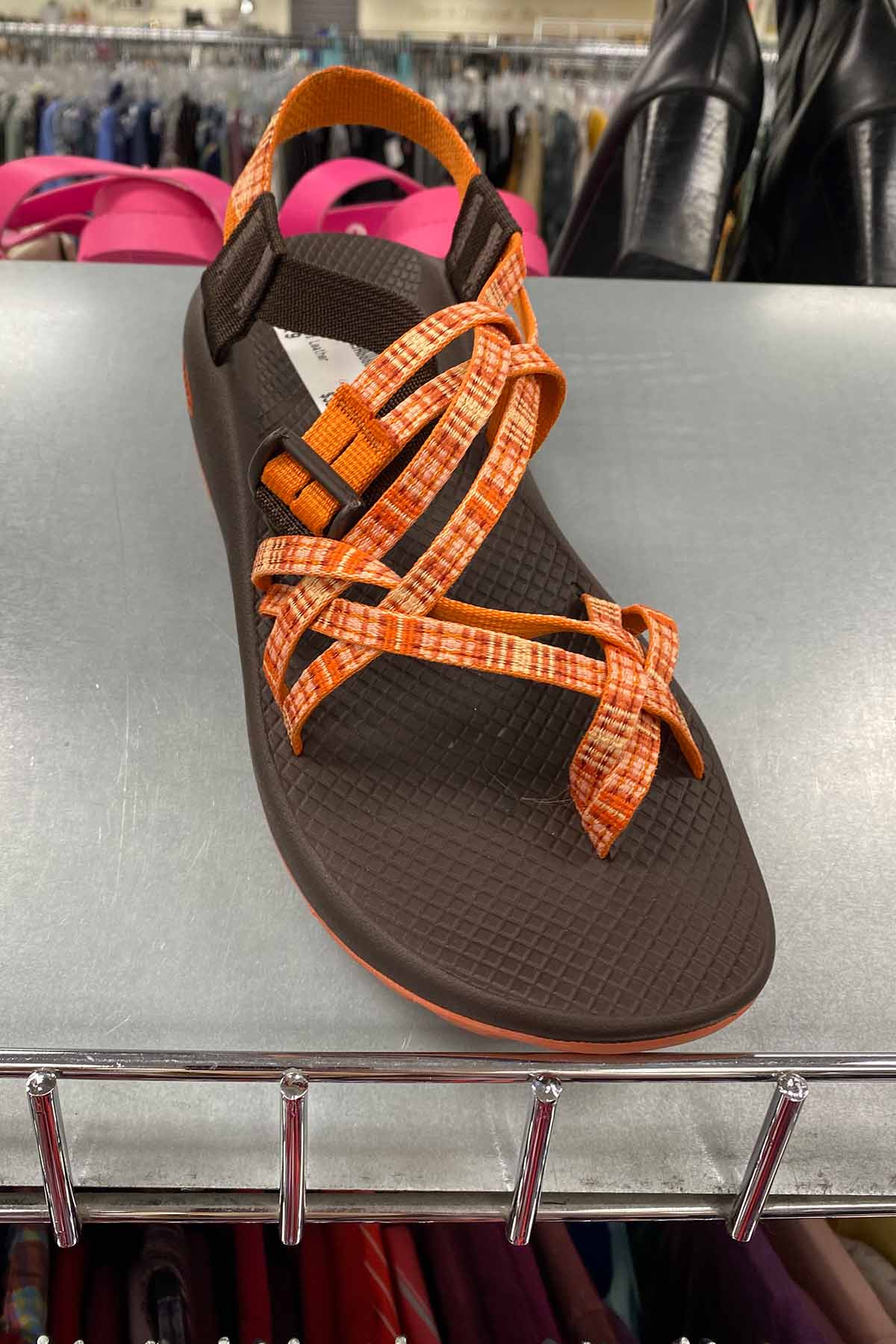 a pair of brown and orange chaco sandals on a shelf.