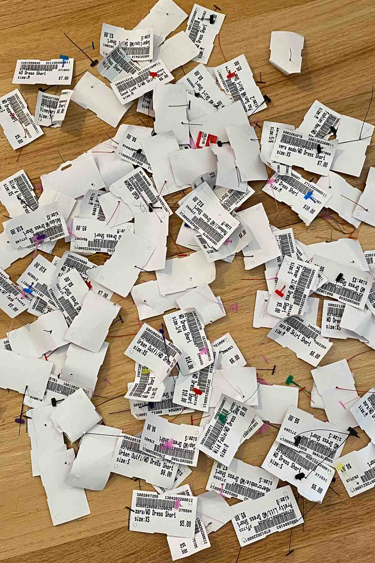 a pile of platos closet clothing tags scattered on the floor.