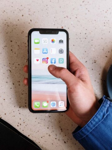 a person holding an iphone showing the home screen with applications.