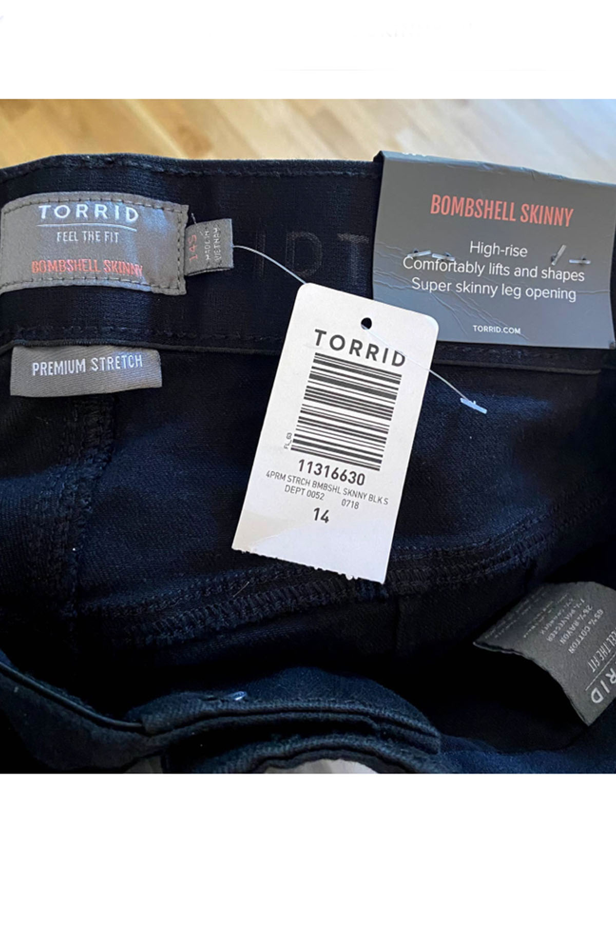 a close up picture of a pair of black torrid pants showing the brand tags.