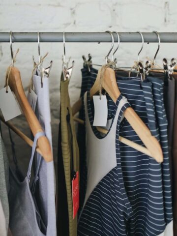 a clothing rack with clothes hanging on wooden hangers.