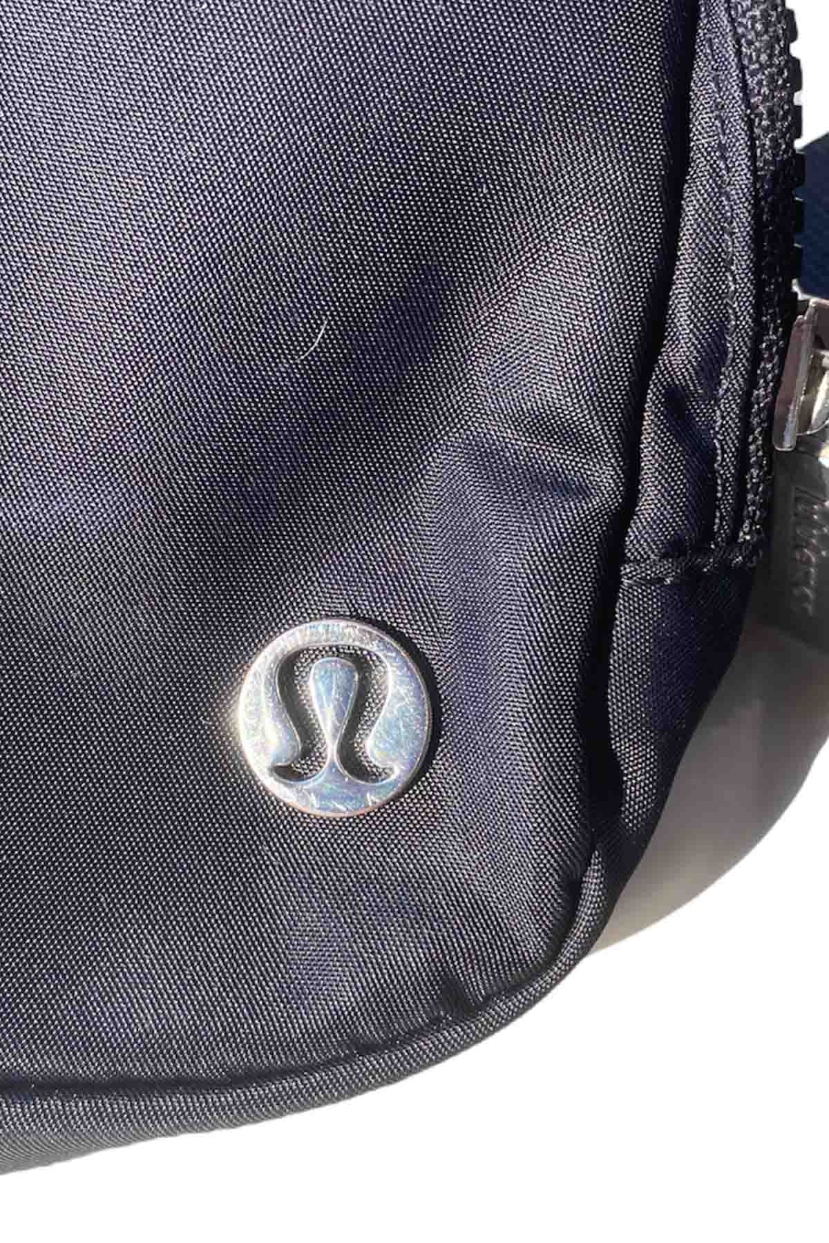 picture of the lululemon logo hardware of a black lululemon belt bag.