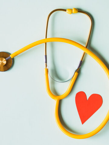 a yellow stethoscope wrapped around a red paper heart.