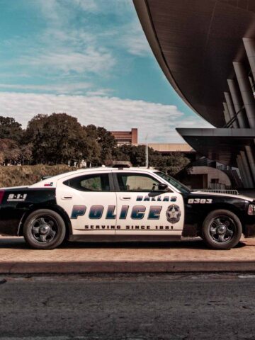 a dallas police officer car sitting on the road in front of an arena.