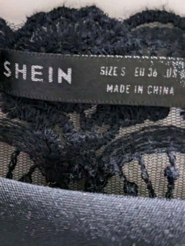 close up picture of a shein brand tag on a black lace top.