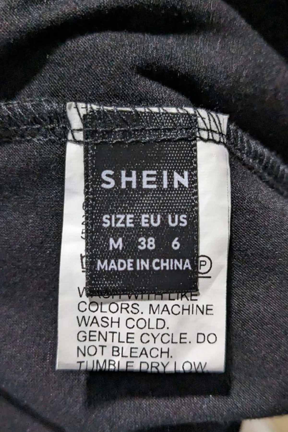 close up picture of a shein size tag on the inside seam of a black shirt.